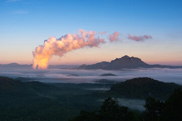 Aerial view Beautiful sea of fog in the mountains, high voltage pole and steam from the coal power plant in the morning sunrise . Mae moh, Lampang, Thailand. Energy and environment concept .