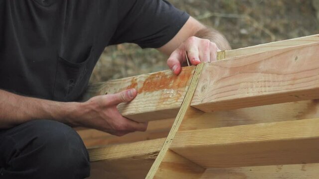 Man Holding Wooden Planks In Place For DIY Mini Skateboard Ramp Project