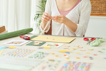 Hands of woman making stars out of colorful paper stripes when creating greeting cards at home