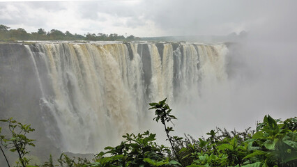 The Zambezi River flows in powerful streams from the plateau into the gorge. Thick fog over the...