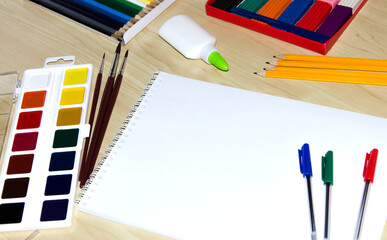 Back to school. The concept of education. Painting. Paints, markers, glue, colored pencils, brushes, with an album for text on the background of the table. Copy space