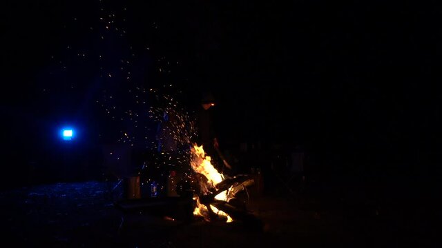Majestic bonfire with rising fire particles at night campsite, handheld view
