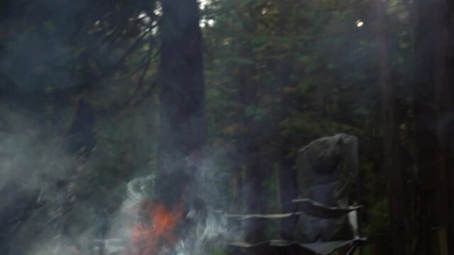 Burning massive wooden log at forest campsite with rising smokes
