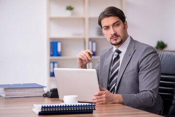Young attractive male employee sitting at workplace