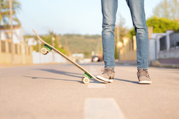 Obraz premium Cropped view of a young man in trainers and jeans with a skateboard. Selective focus