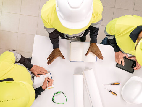 Top view of a group of a multiethnic people at work wearing helmets. Selective focus
