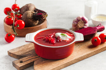 Delicious fresh red borscht, garlic, tomatoes and beets on the kitchen table.