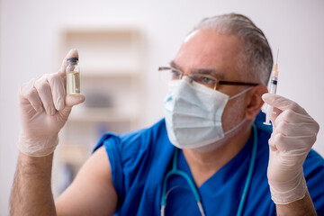 Old male doctor in vaccination concept
