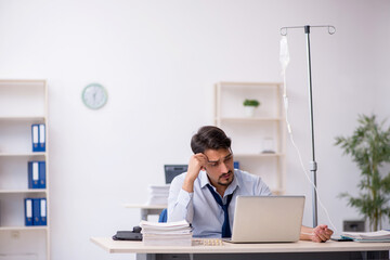 Young male employee suffering at workplace