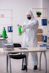 Young male contractor disinfecting office during pandemic