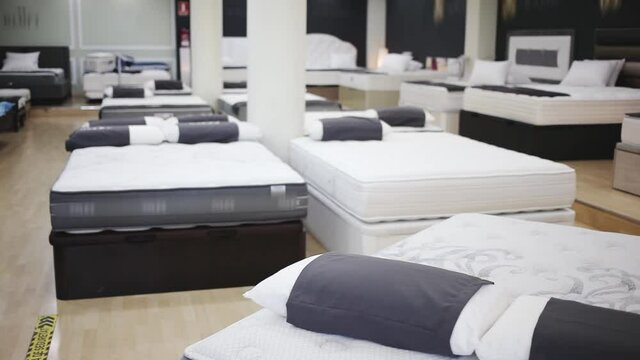 Closeup of new modern orthopaedic mattress on display for sale in large furniture store. High quality FullHD footage