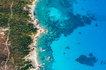 Fototapeta premium View from above, stunning aerial view of a green and rocky coastline bathed by a turquoise, crystal clear water.Sardinia, Italy.