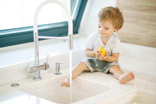 The child washes his hands. Little boy plays with tap water. High quality photo