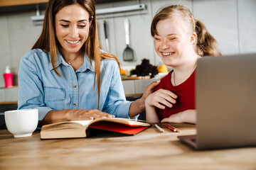 White woman helping her daughter with down syndrome doing homework