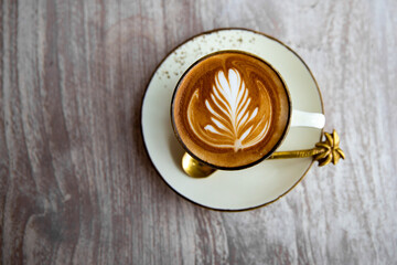 Hot white cup of cappuccino with latte art on wooden table