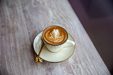 Hot white cup of cappuccino with latte art on wooden table