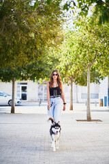 Young stylish woman taking her siberian husky for a ride in city