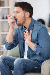man using asthma inhaler at home