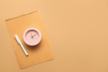 Alarm clock with paper sheet and pen on color background