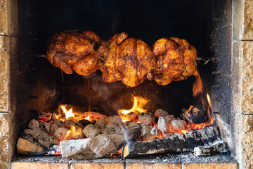 chicken roasting on a spit in garden grill with open fire - obrazy, fototapety, plakaty