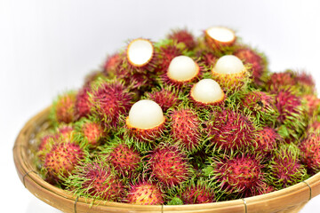 Rambutan, Thai fruits in a bamboo basket placed on white background. Fresh rambutan summer fruit from garden in Thailand. selected focus