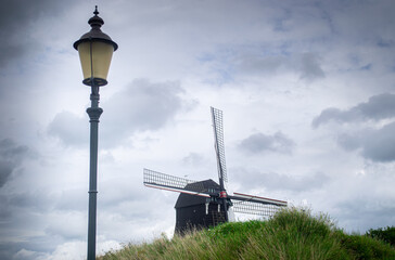 Holenderski wiatrak na pagórku oraz na tle pochmurnego nieba