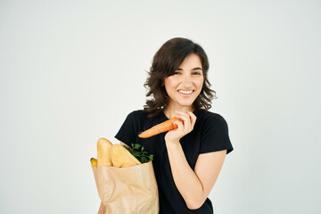 cheerful brunette in a black t-shirt with a package of products carrots in the hands of vegetables