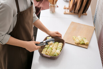 Woman preparing tasty stuffed cabbage rolls in kitchen, closeup