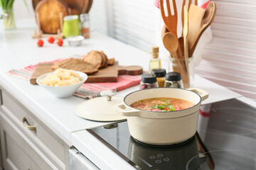 Cooking pot with tasty sauerkraut soup on electric stove in kitchen