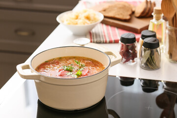 Cooking pot with tasty sauerkraut soup on electric stove in kitchen