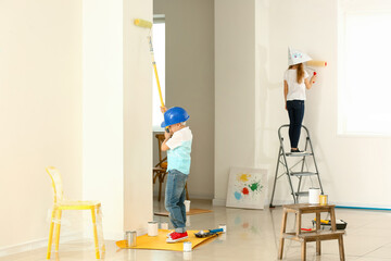 Little children painting wall in room