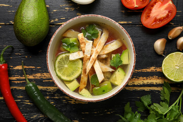 Composition with tasty Sopa de Lima soup on dark wooden background