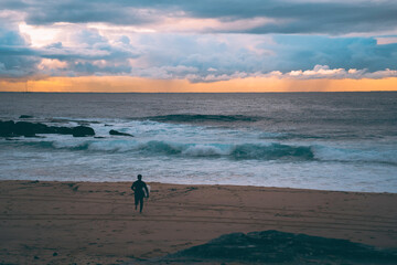 Fototapeta na wymiar silhouette of surfer walking along the beach
