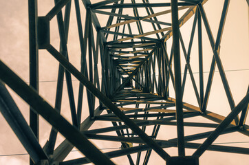 Abstract geometric composition of metal beams and angles against a multicolored sky. Metal high-voltage pole. Inside view, Bottom-up. Industry