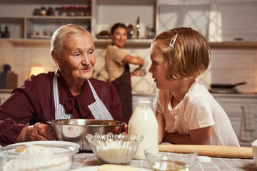 Experienced grandmother instructing girl about cooking at home