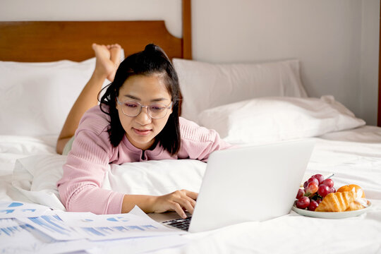 work from home, a young Asian woman who works in finance at home calculates financial graphs showing the results of his investments, planning the steps of his business growth