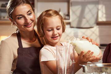Mother watching her daughter pouring milk to measuring cup
