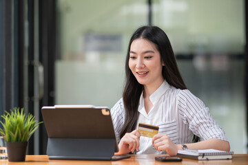 Young woman holding credit card and using a laptop computer. Online shopping concept