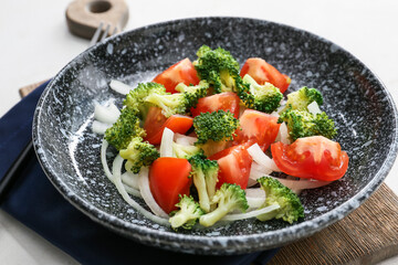 Plate of tasty salad with broccoli on light background