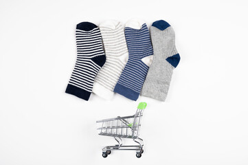 Little baby socks over shopping cart isolated on white. Consumer shopping concept