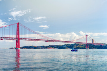 Fototapeta premium Portugal Travel Ideas. One Blue Sailing Boat With Group of Tourist on Tagus River Under 25th of April Bridge in Lisbon