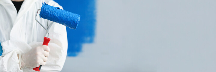 Man builder repairman holding roller with blue paint in his hands closeup