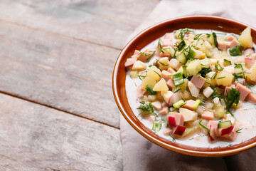 Bowl with tasty okroshka on wooden background