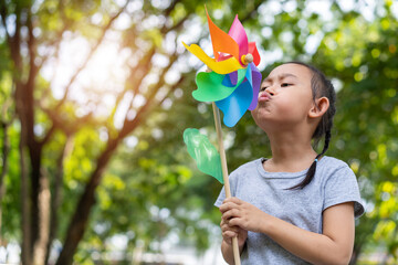 Asian little girl playing with paper windmill