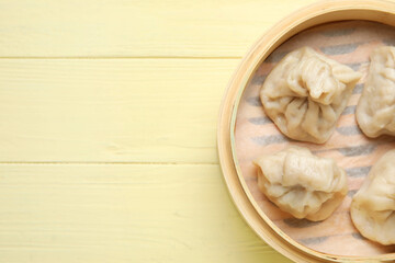 Bamboo steamer with tasty dumplings on color wooden background