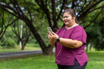 Fat woman asian holding smart phone with listening to music. Exercise outdoors for weight loss idea concept