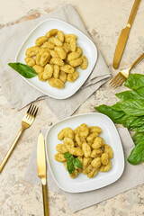 Plates with tasty pesto gnocchi on light background