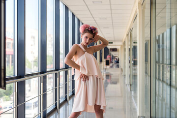 Woman in fashion pink dress and white shoes posing in corridor