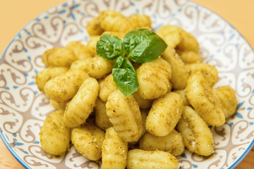 Plate with tasty pesto gnocchi on table, closeup