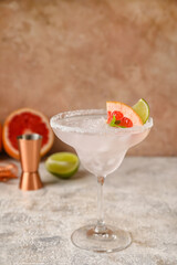 Glass of tasty grapefruit margarita on light background
